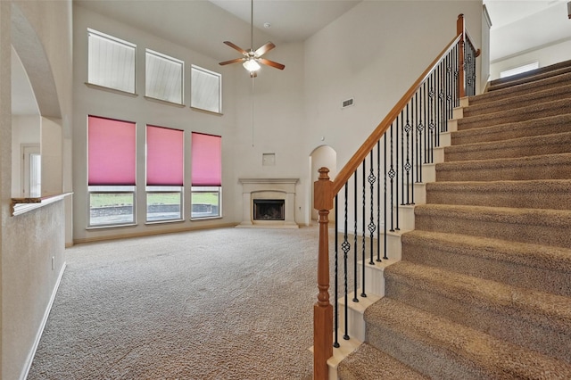 6824 San Fernando Dr, Fort Worth, TX 76131 - stairs with a fireplace with raised hearth, carpet, ceiling fan, a towering ceiling, and baseboards