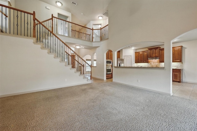 6824 San Fernando Dr, Fort Worth, TX 76131 - unfurnished living room with light colored carpet, a towering ceiling, stairs, baseboards, and arched walkways