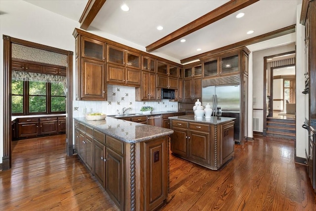 6908 Ridgewood Dr, Fort Worth, TX 76132 - kitchen featuring appliances with stainless steel finishes, beam ceiling, dark stone counters, tasteful backsplash, and dark wood-style floors