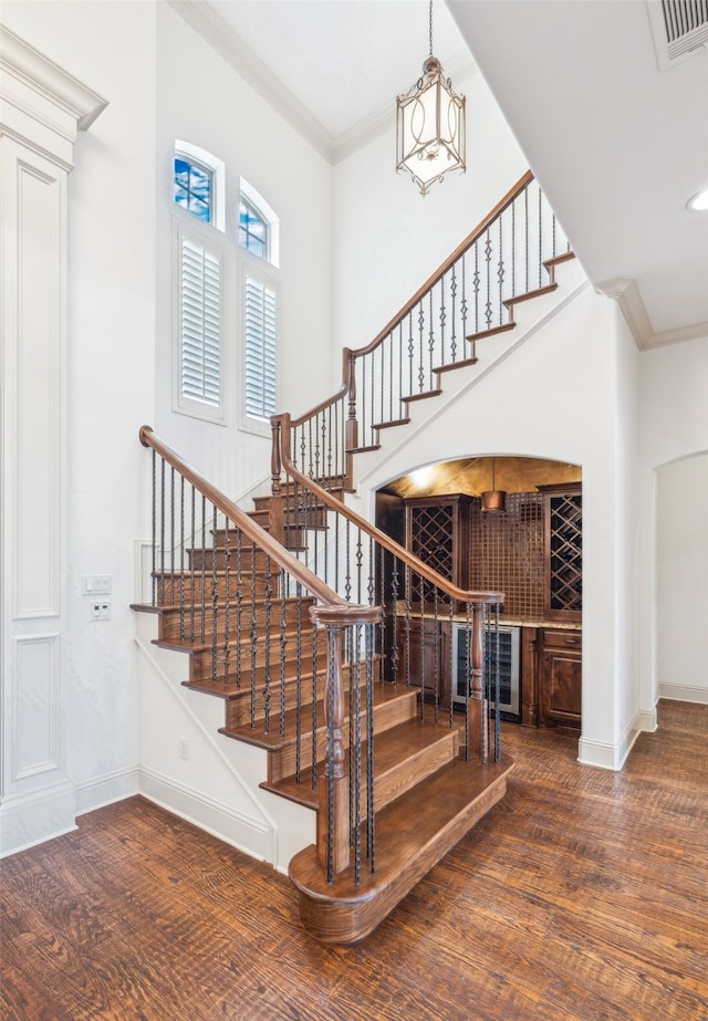 stairs featuring wood finished floors, ornamental molding, baseboards, and recessed lighting