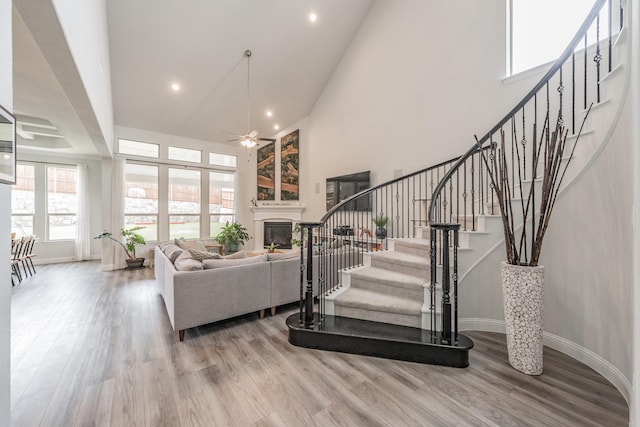 233 Honey Brook Ln, Aledo, TX 76008 - staircase featuring a towering ceiling, ceiling fan, a glass covered fireplace, wood finished floors, and baseboards
