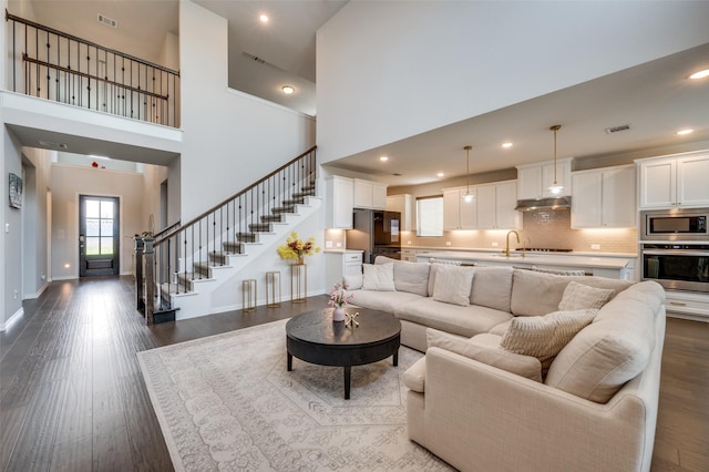 624 Cedarwood St, Little Elm, TX 76227 - living room featuring stairway, dark wood-style flooring, a towering ceiling, baseboards, and recessed lighting