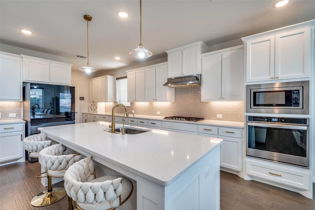 624 Cedarwood St, Little Elm, TX 76227 - kitchen featuring stainless steel appliances, a sink, decorative backsplash, under cabinet range hood, and dark wood-style floors