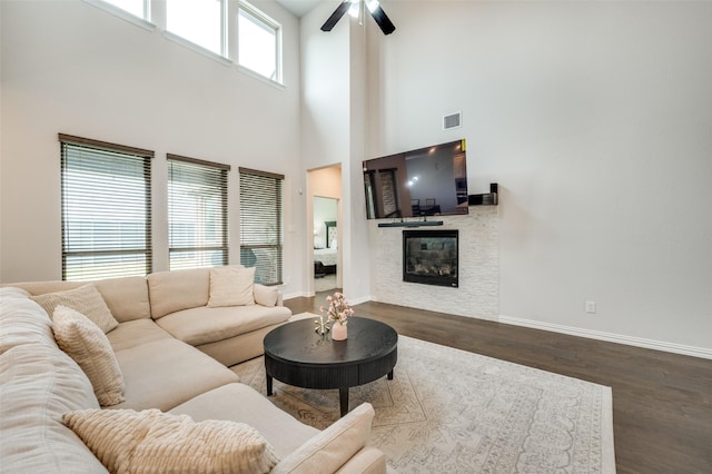 624 Cedarwood St, Little Elm, TX 76227 - living area featuring wood finished floors, ceiling fan, a towering ceiling, baseboards, and a glass covered fireplace