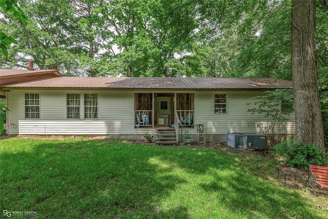 single story home featuring covered porch, central air condition unit, a front yard, and metal roof