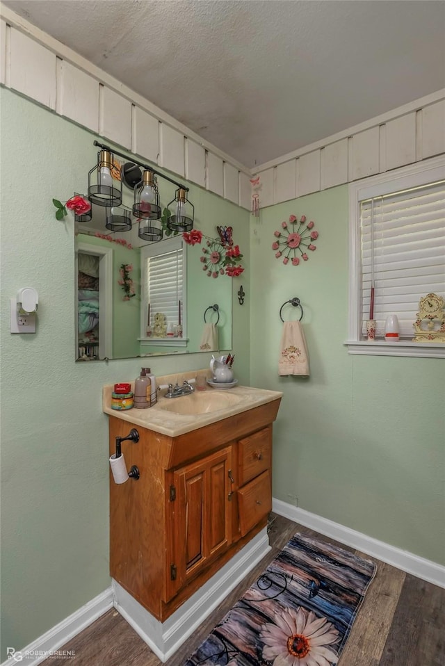 bathroom featuring baseboards, wood finished floors, vanity, and a textured ceiling
