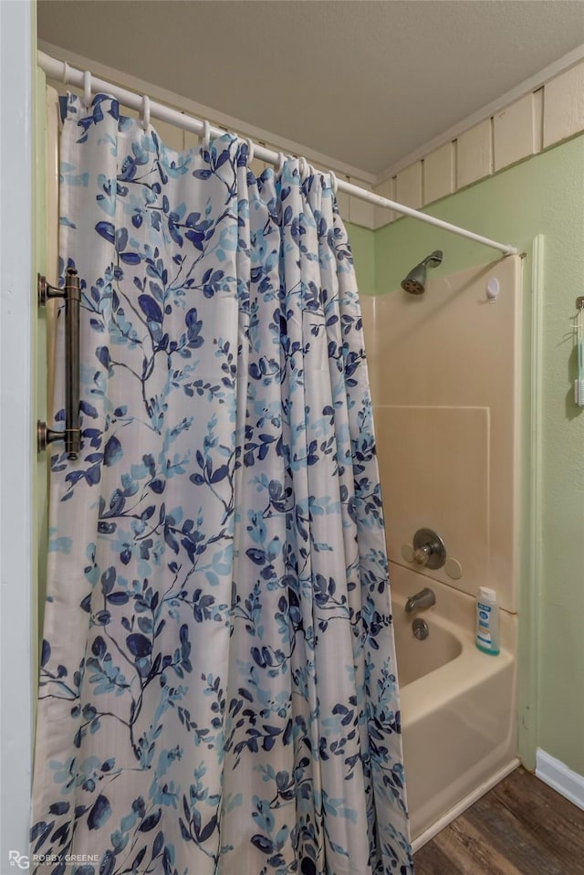 bathroom featuring wood finished floors and shower / bathtub combination with curtain