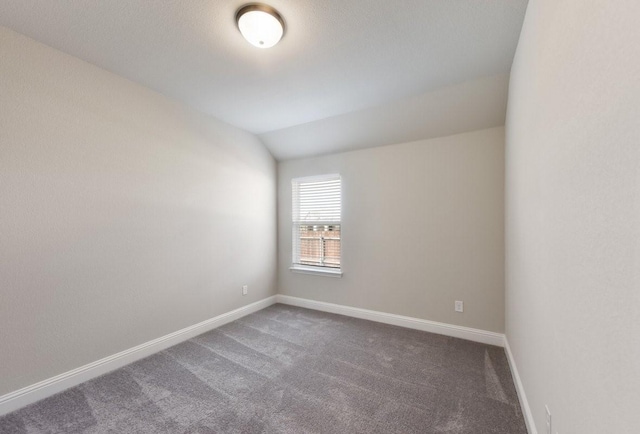 carpeted spare room featuring baseboards and lofted ceiling
