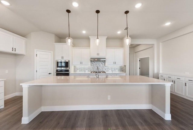 kitchen with white cabinetry, decorative backsplash, a spacious island, dark wood-style floors, and vaulted ceiling