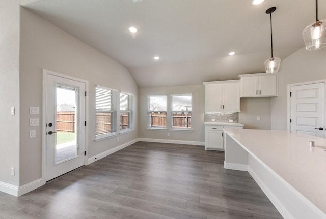 kitchen featuring vaulted ceiling, white cabinets, dark wood finished floors, light countertops, and decorative light fixtures