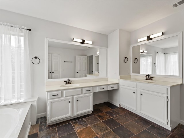 3000 Clearmeadow Dr, Mesquite, TX 75181 - full bath with two vanities, baseboards, stone finish flooring, and a tub