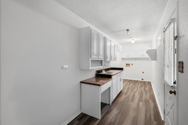 104 Murls Lake Rd, Weatherford, TX 76085 - kitchen featuring a sink, dark wood-style floors, dark countertops, a textured ceiling, and baseboards