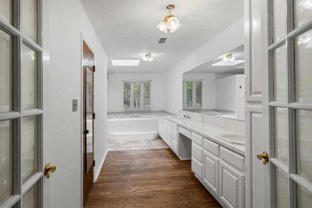 104 Murls Lake Rd, Weatherford, TX 76085 - bathroom featuring a textured ceiling, wood finished floors, a garden tub, and double vanity