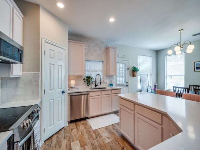 976 Fox Grove Ln, Providence Village, TX 76227 - kitchen featuring stainless steel appliances, a sink, light countertops, light wood finished floors, and tasteful backsplash