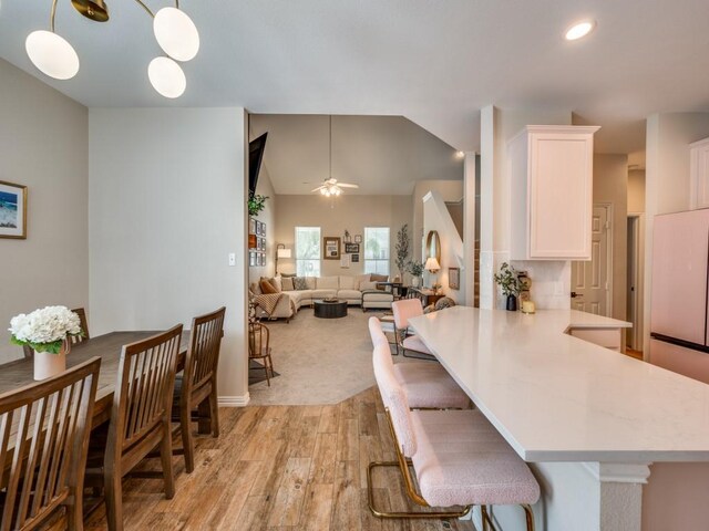 976 Fox Grove Ln, Providence Village, TX 76227 - kitchen with light wood-style flooring, white cabinets, light countertops, a kitchen bar, and ceiling fan