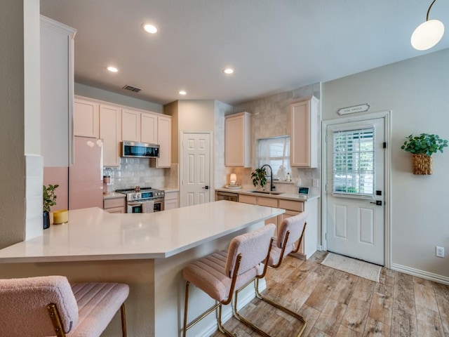 976 Fox Grove Ln, Providence Village, TX 76227 - kitchen featuring appliances with stainless steel finishes, a sink, a peninsula, backsplash, and light countertops
