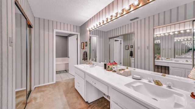 5122 La Vista Ct, Granbury, TX 76049 - bathroom with wallpapered walls, a textured ceiling, a soaking tub, double vanity, and tile patterned floors