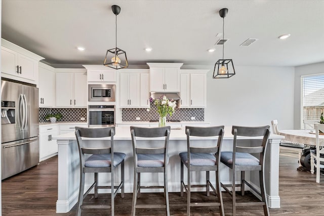 2540 Bottlebrush Dr, Prosper, TX 75078 - kitchen with stainless steel appliances, light countertops, backsplash, white cabinets, and a center island