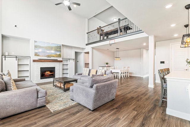 2540 Bottlebrush Dr, Prosper, TX 75078 - living room featuring dark wood-style floors, baseboards, ceiling fan, a towering ceiling, and a stone fireplace