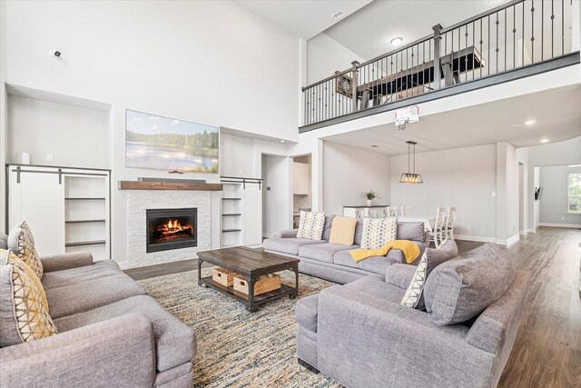 2540 Bottlebrush Dr, Prosper, TX 75078 - living area with wood finished floors, a towering ceiling, a stone fireplace, baseboards, and recessed lighting