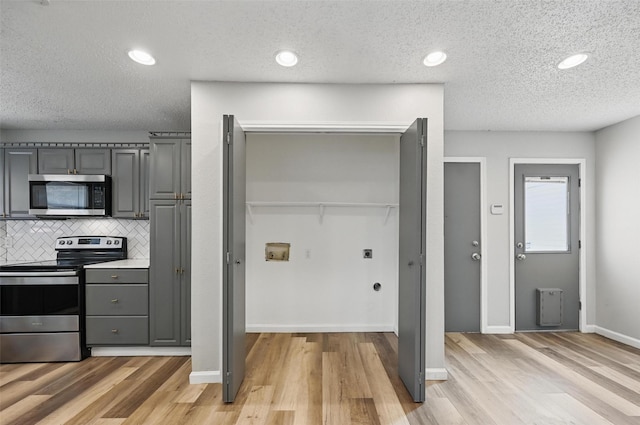 8805 Wood Glen Dr, Rowlett, TX 75088 - kitchen with stainless steel appliances, gray cabinets, a textured ceiling, light wood-style floors, and decorative backsplash