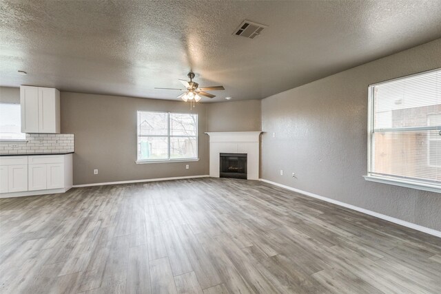 4032 Red Rock, Heartland, TX 75126 - unfurnished living room featuring a ceiling fan, light wood-style flooring, a textured ceiling, a tile fireplace, and baseboards