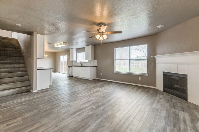 4032 Red Rock, Heartland, TX 75126 - unfurnished living room featuring a sink, wood finished floors, a textured ceiling, a ceiling fan, and a tiled fireplace