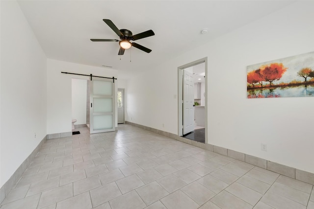 10166 San Lorenzo Dr, Dallas, TX 75228 - spare room featuring a barn door, a ceiling fan, light tile patterned flooring, a smoke detector, and baseboards