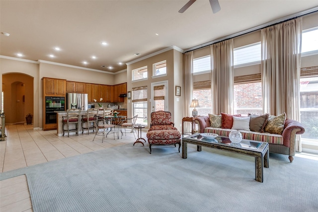 3671 Navarro Way, Frisco, TX 75034 - living area with arched walkways, ornamental molding, a ceiling fan, light tile patterned flooring, and light carpet