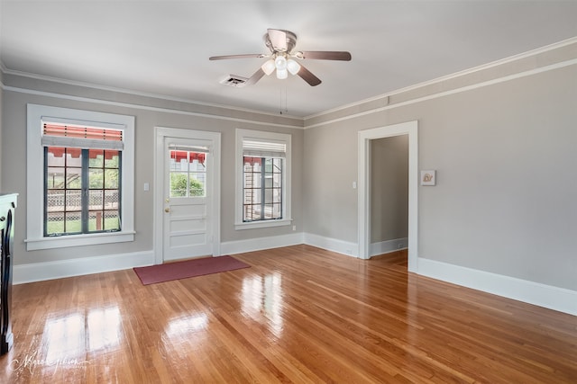 empty room with ornamental molding, ceiling fan, light wood-type flooring, and baseboards