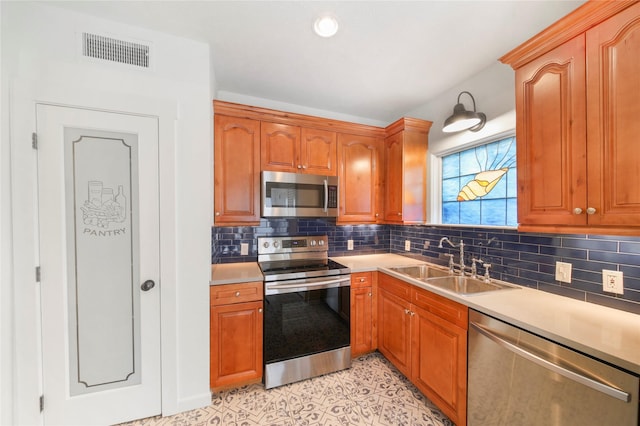 kitchen with stainless steel appliances, a sink, light countertops, decorative backsplash, and brown cabinets