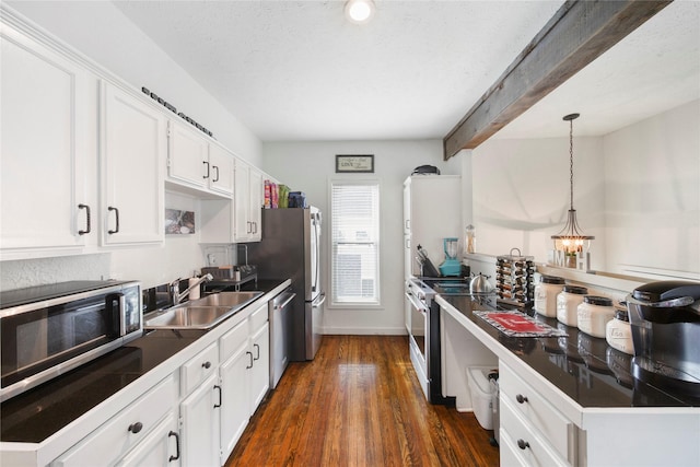 kitchen featuring a sink, appliances with stainless steel finishes, dark countertops, and white cabinets