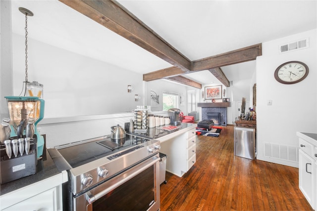 kitchen with stainless steel electric stove, white cabinets, a brick fireplace, beamed ceiling, and dark wood-type flooring