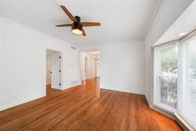 unfurnished room with ceiling fan, wood finished floors, a chandelier, ornamental molding, and baseboards