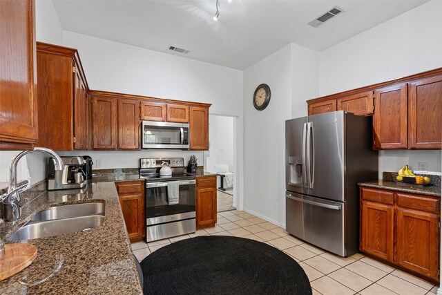 221 Whitestone Way, Weatherford, TX 76085 - kitchen with appliances with stainless steel finishes, light tile patterned floors, dark stone countertops, and brown cabinets