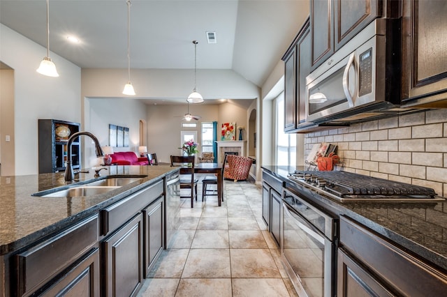2617 Castle Creek Dr, Little Elm, TX 75068 - kitchen featuring a sink, stainless steel appliances, dark brown cabinetry, decorative backsplash, and vaulted ceiling