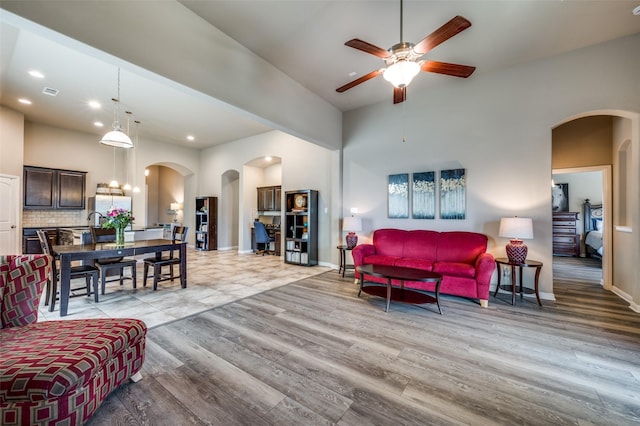 2617 Castle Creek Dr, Little Elm, TX 75068 - living area featuring arched walkways, ceiling fan, light wood-style flooring, a towering ceiling, and baseboards