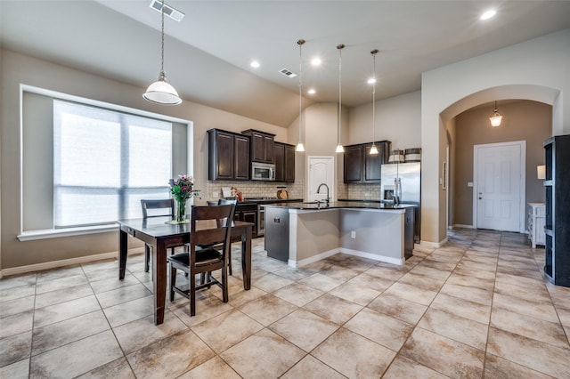 2617 Castle Creek Dr, Little Elm, TX 75068 - kitchen with appliances with stainless steel finishes, dark countertops, arched walkways, backsplash, and dark brown cabinets