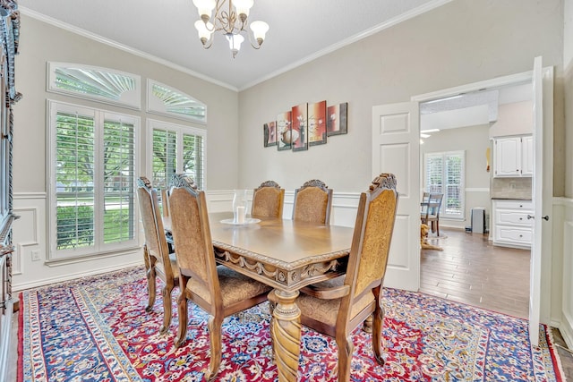 dining area featuring a chandelier, ornamental molding, wainscoting, and light wood finished floors