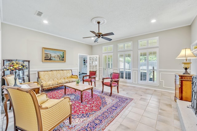 living area featuring ornamental molding, a ceiling fan, wainscoting, a decorative wall, and recessed lighting