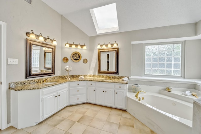 bathroom with a skylight, lofted ceiling, a jetted tub, double vanity, and tile patterned floors