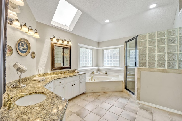 full bath featuring a skylight, a textured ceiling, lofted ceiling, a shower stall, and double vanity