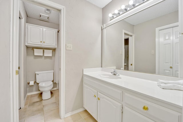 bathroom featuring toilet, a textured ceiling, vanity, tile patterned flooring, and baseboards