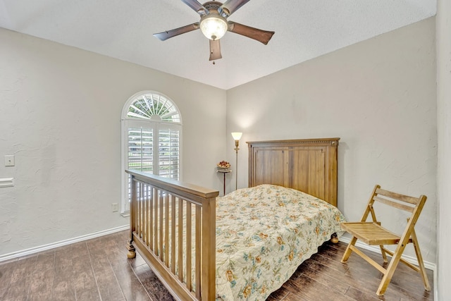 bedroom featuring wood finished floors, baseboards, a ceiling fan, and a textured wall