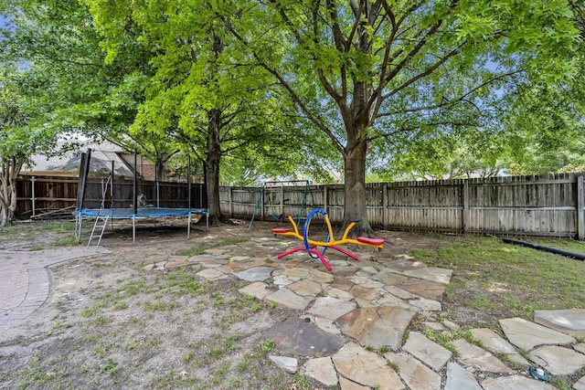 fenced backyard featuring a trampoline