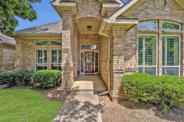 entrance to property with brick siding and roof with shingles