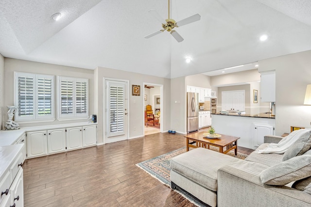 living area with ceiling fan, wood finished floors, high vaulted ceiling, recessed lighting, and baseboards