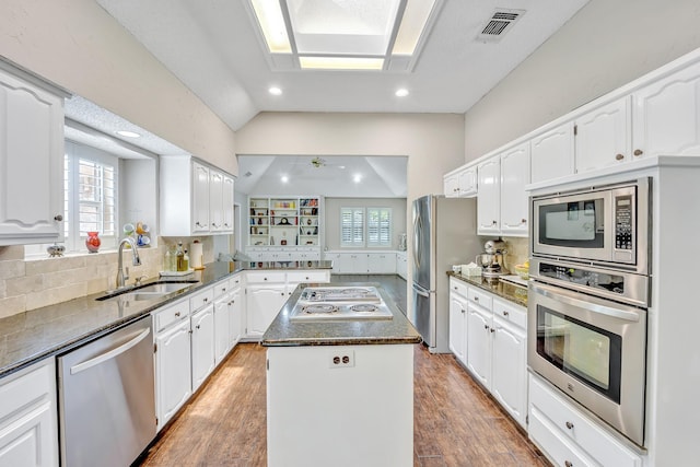 kitchen with appliances with stainless steel finishes, a center island, lofted ceiling, a sink, and white cabinets