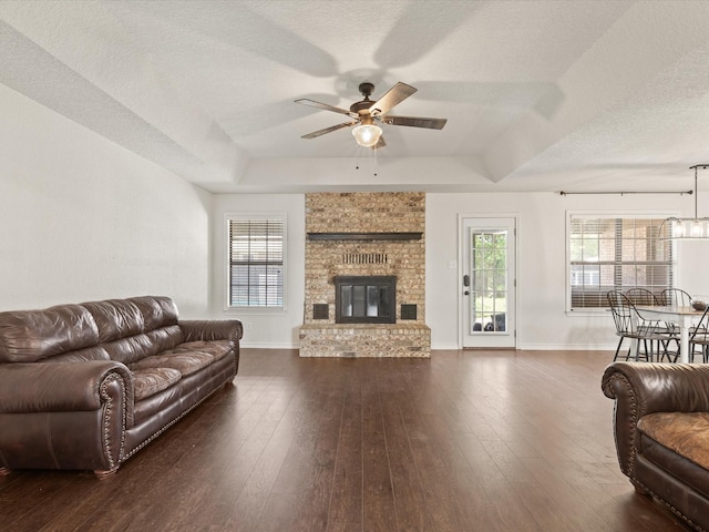 402 Brookview Dr, Decatur, TX 76234 - living area featuring a textured ceiling, a ceiling fan, a tray ceiling, baseboards, and dark wood-style flooring