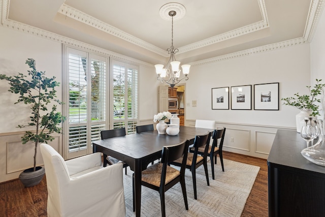 1141 Yorkshire Dr, Carrollton, TX 75007 - dining room with a raised ceiling, dark wood-style flooring, a decorative wall, a chandelier, and wainscoting